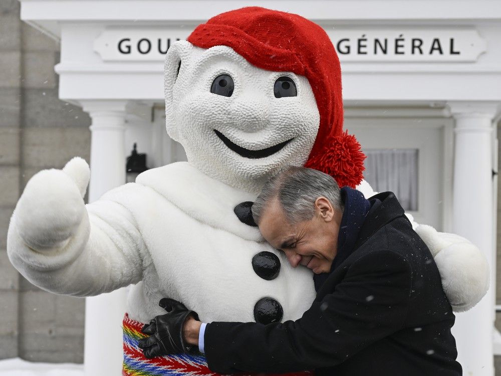  Prime Minister Mark Carney, right, and Bonhomme Carnaval hug at the beginning of a Cabinet planning forum in front of the Governor General summer residence at the Citadelle in Quebec City, Thursday, Jan. 22, 2026.