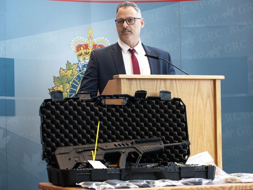 Firearms and ammunition are visible in front of RCMP Corporal Mitch Rondeau as he speaks to the media about an extortion investigation undertaken by the Parkland General Investigation Section, in Edmonton Friday Feb. 27, 2026. Photo by David Bloom