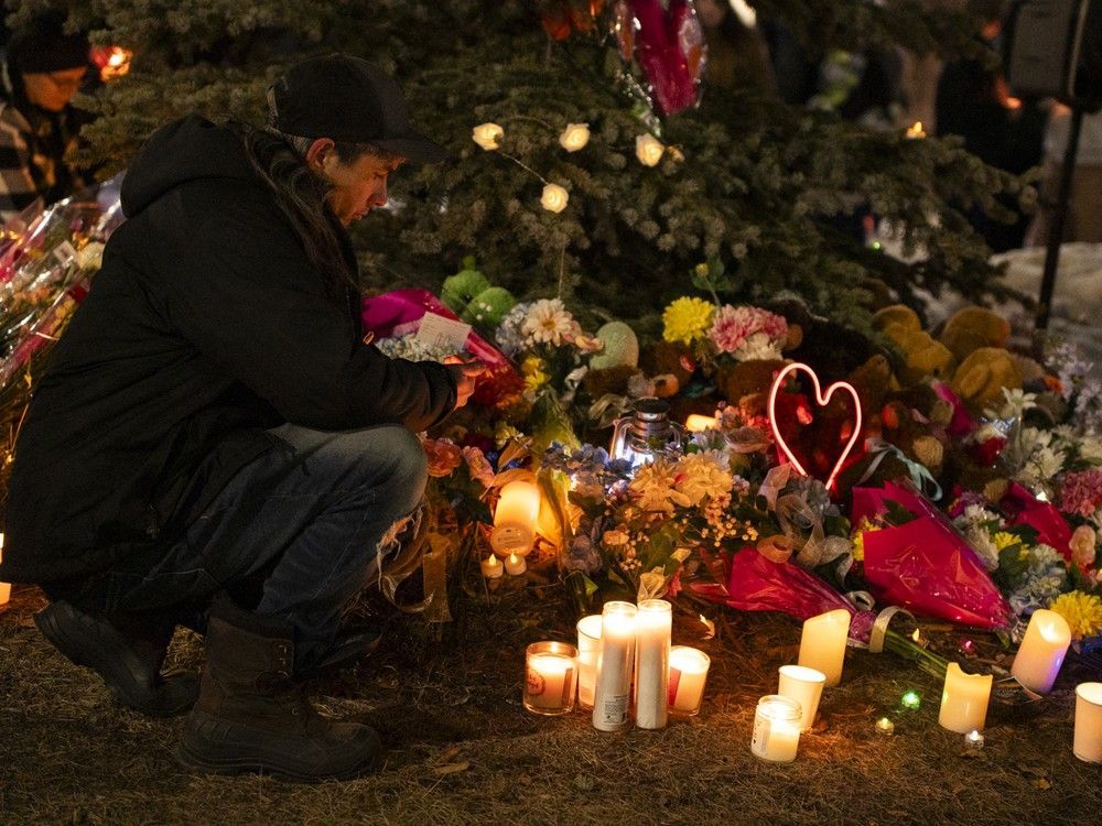 A member of the community places flowers at a memorial during a candlelight vigil for the victims of Tumbler Ridge Secondary School where a mass shooting took place a day earlier, in the small town of Tumbler Ridge on February 11, 2026.