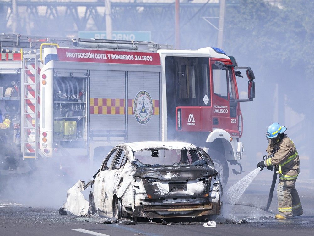  A firefighter extinguishes a car on fire on February 22, 2026 in Guadalajara, Mexico.