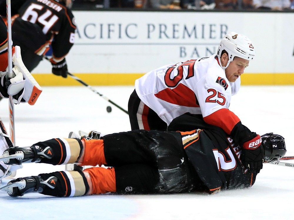 Ottawa Senators bruiser Chris Neil drives an opponent into the ice during an NHL game.