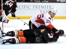 Ottawa Senators bruiser Chris Neil drives an opponent into the ice during an NHL game.