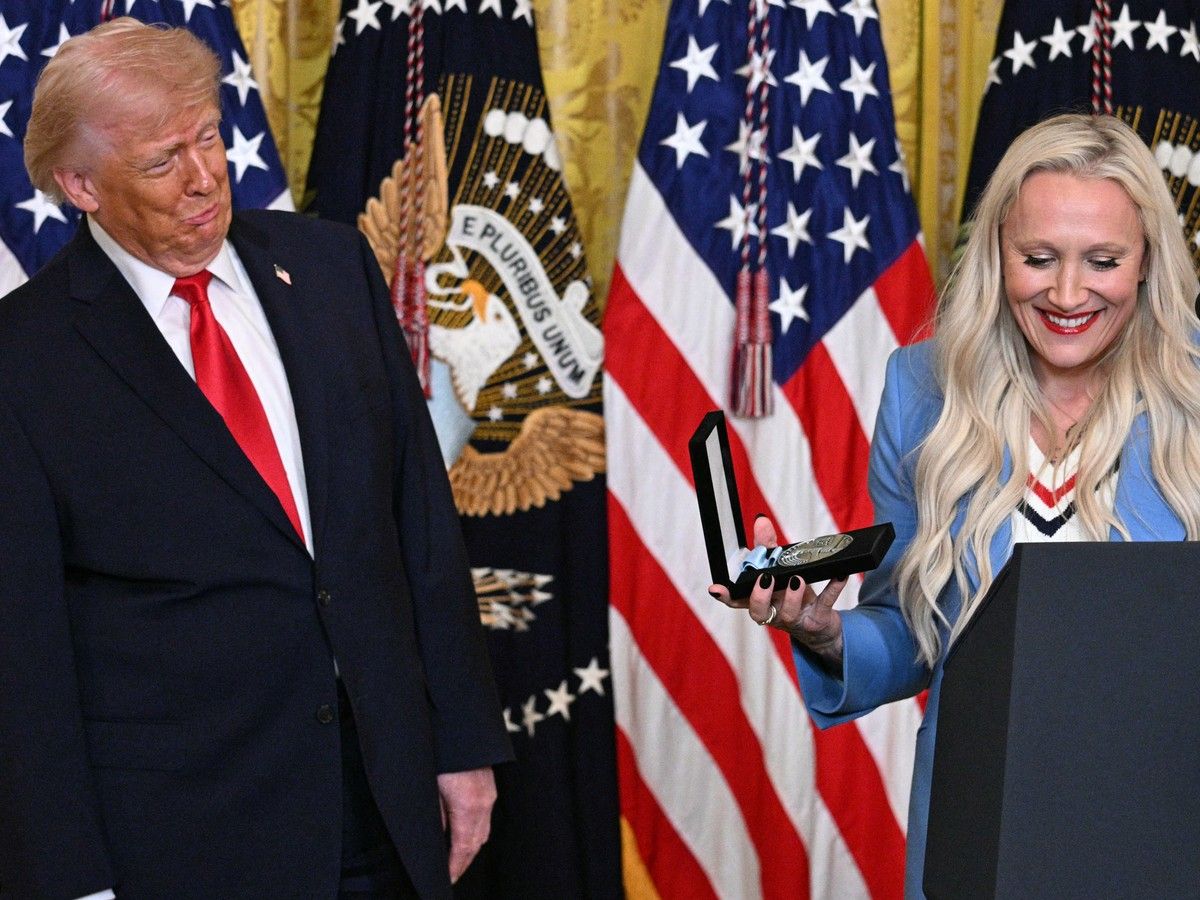 U.S. President Donald Trump (L) reacts as U.S. bobsledder Kaillie Humphries announces she is awarding him with an Ikkos award during a Women’s History Month event in the East Room of the White House in Washington, DC, on March 12, 2026.