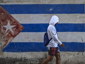 A person walking past a Cuban flag painted on a wall