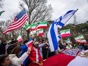 Protesters wave U.S. and Israeli flags and pre-revolution Iranian flags in front the Iranian Embassy in The Hague.