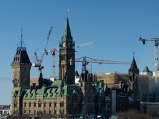 Parliament Hill surrounded by several cranes under a blue sky.