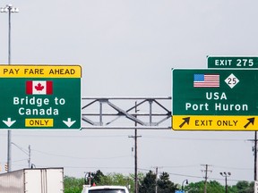 A road sign with a Canadian flag reading 'Bridge to Canada' next to a sign with an American flag reading 'USA Port Huron'.