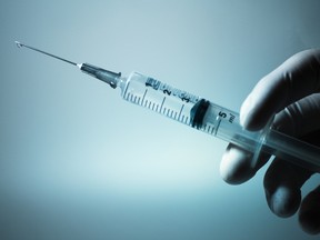 A gloved hand holding a syringe.