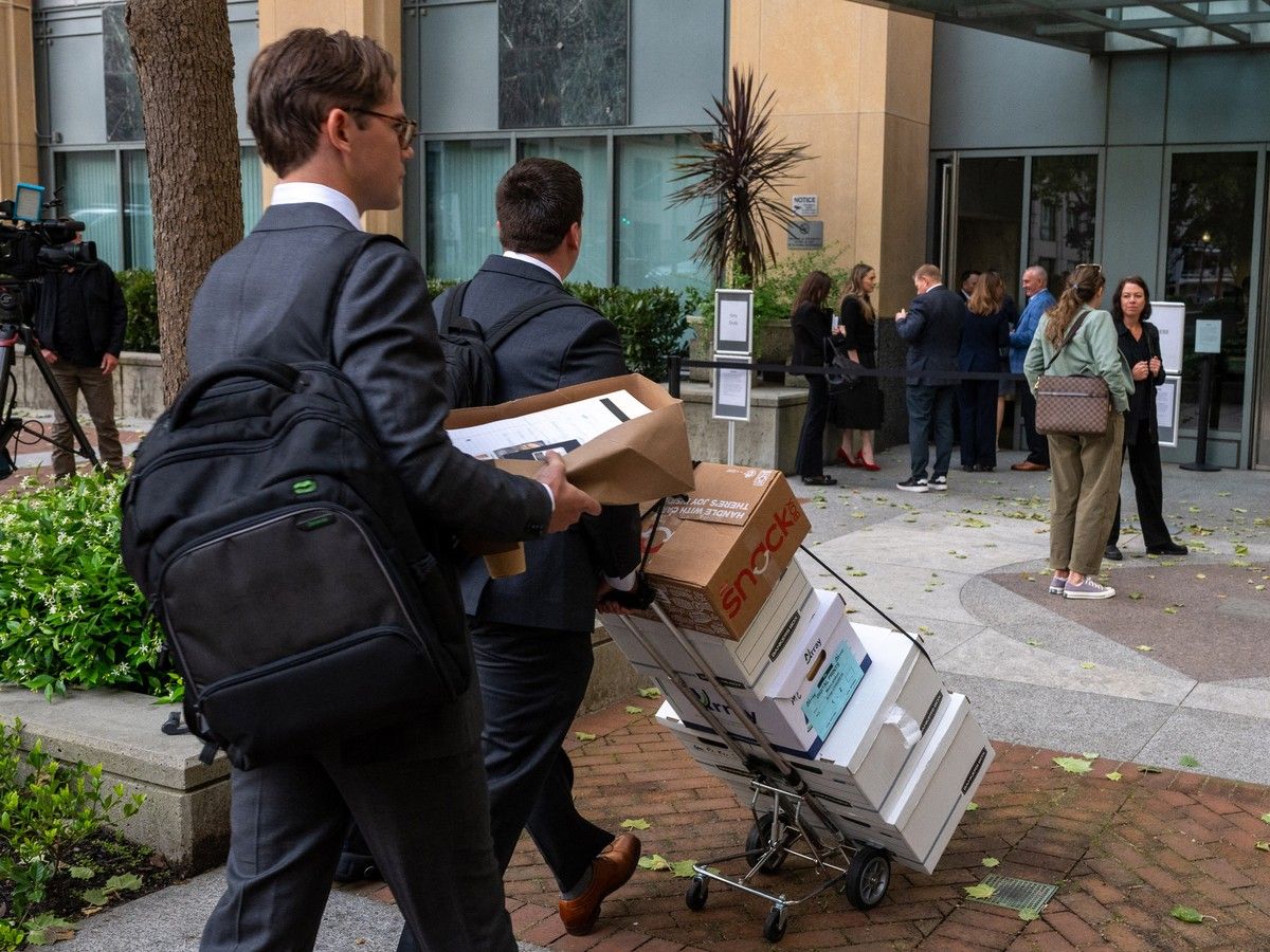 A man wheels boxes on a dolly into a building