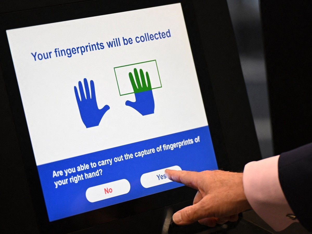  A person uses the Automated European Union Entry/Exit System (EES) kiosk at Eurotunnel, south east England (Photo by Justin TALLIS / AFP)
