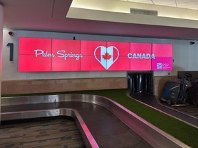A screen reading 'Palm Springs loves Canada' above an airport baggage carousel.