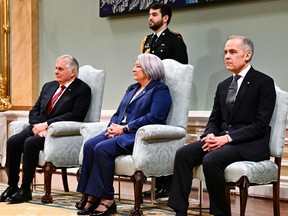 Whit Fraser, Mary Simon, Mark Carney seated, with a CF soldier behind them