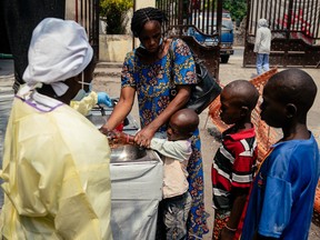 A mother helps her children wash their hands