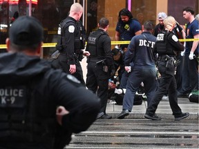 Police officers tend to a wounded man on a sidewalk
