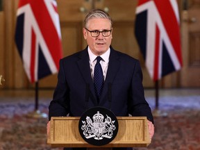 Keir Starmer standing behind a lectern with Union Jacks in the background.