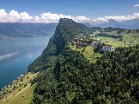 A hotel on a moutain with a lake in the background.