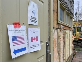 An emergency exit on the side of Haskell Library with signs stuck on the front indicating the entract for Canadian and U.S. visitors.