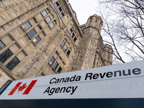 A sign for the Canada Revenue Agency outside a stone building.