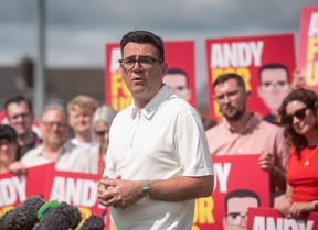 Andy Burnham speaking in front of supporters holding placards with his name on.