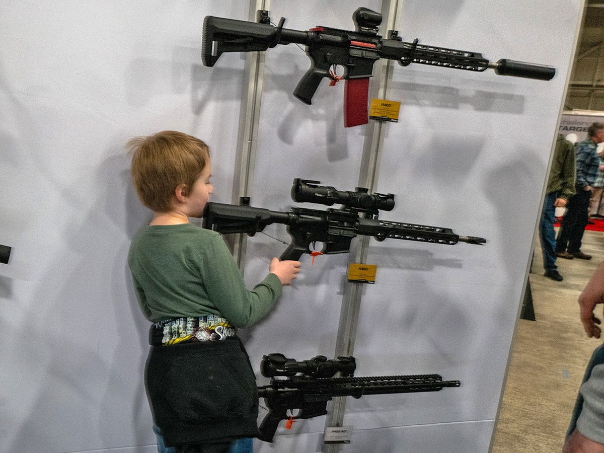 Child looking at secured assault weapons.