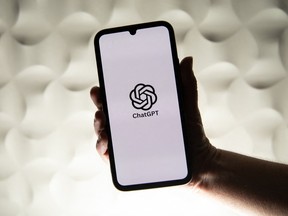 A person holding up a phone with the ChatGPT logo on the screen.