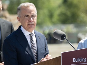 Mark Carney standing behind a lectern in the River District in Vancouver.