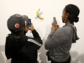 People post in front of Maurizio Cattelan's