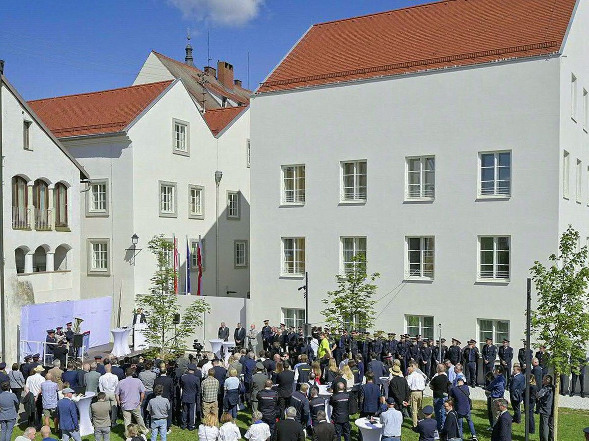 A crowd of people gathered on a lawn outside a white building.