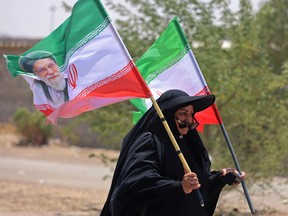 An Iranian pilgrim carrying a flag with a portrait of Iran's slain supreme leader Ali Khamenei, walks toward Karbala to participate in the Arbaeen pilgrimage after crossing through the Iraq-Iran border at Zurbatiyah, south of Baghdad on July 29, 2026.