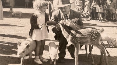 RCMP Supt. Joe Atherton crouching next to his niece, Janan, while feeding two fawns.