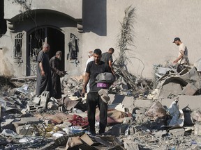 People walk through rubble.
