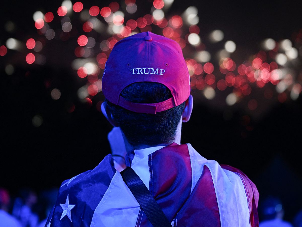 A youth wearing a Trump hat watches an America 250 fireworks display.