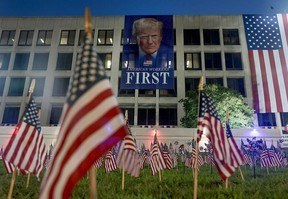 Trump banner on building with flags in grass in foreground