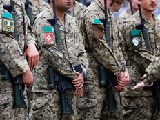 Members of Canadian Armed Forces in uniform stood in a line and each holding a rifle.
