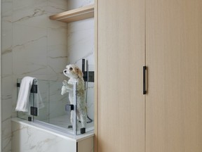Large-format marble-look tile wraps this mud room and built in pet zone in quiet luxury.