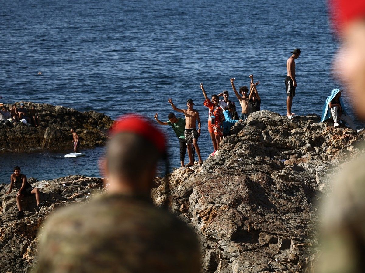 Infantry forces watch a group of migrants near the border post of the Spanish enclave of Ceuta