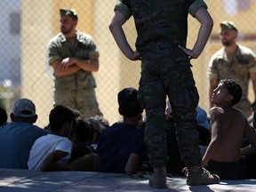A young migrant looks at a member of the Spanish Army's 'Regulares' infantry