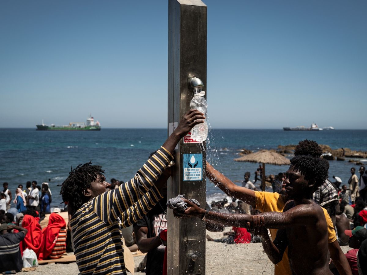 Migrants fill bottles with water on the beach next to the CETI (Centros de Estancia Temporal de Inmigrantes) on August 2, 2026 in Ceuta, Spain.