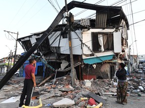 A couple stands amid the rubble of a collapsed house after an earthquake