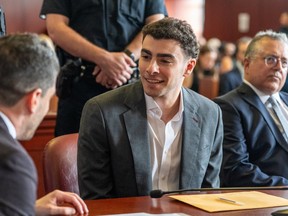 Luigi Mangione in court, smiling and talking to a man sat next to him.