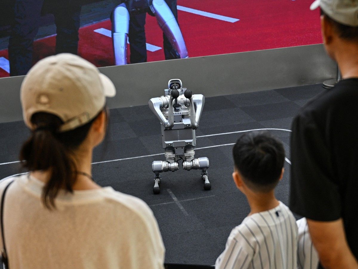  People look at a remote-controlled Go2 robot by Unitree Robotics while visiting the Unitree Robotics Embodied Intelligence Experience Center in the Jing’an district in Shanghai on Aug. 19, 2026.