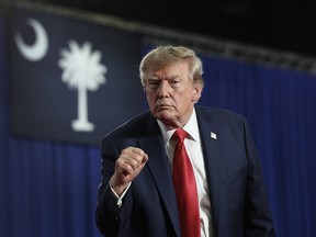 Donald Trump makes a fist while standing on a stage.