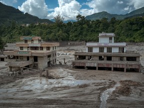 Two dilapidated buildings surrounded by mud after a flood in Nepal.