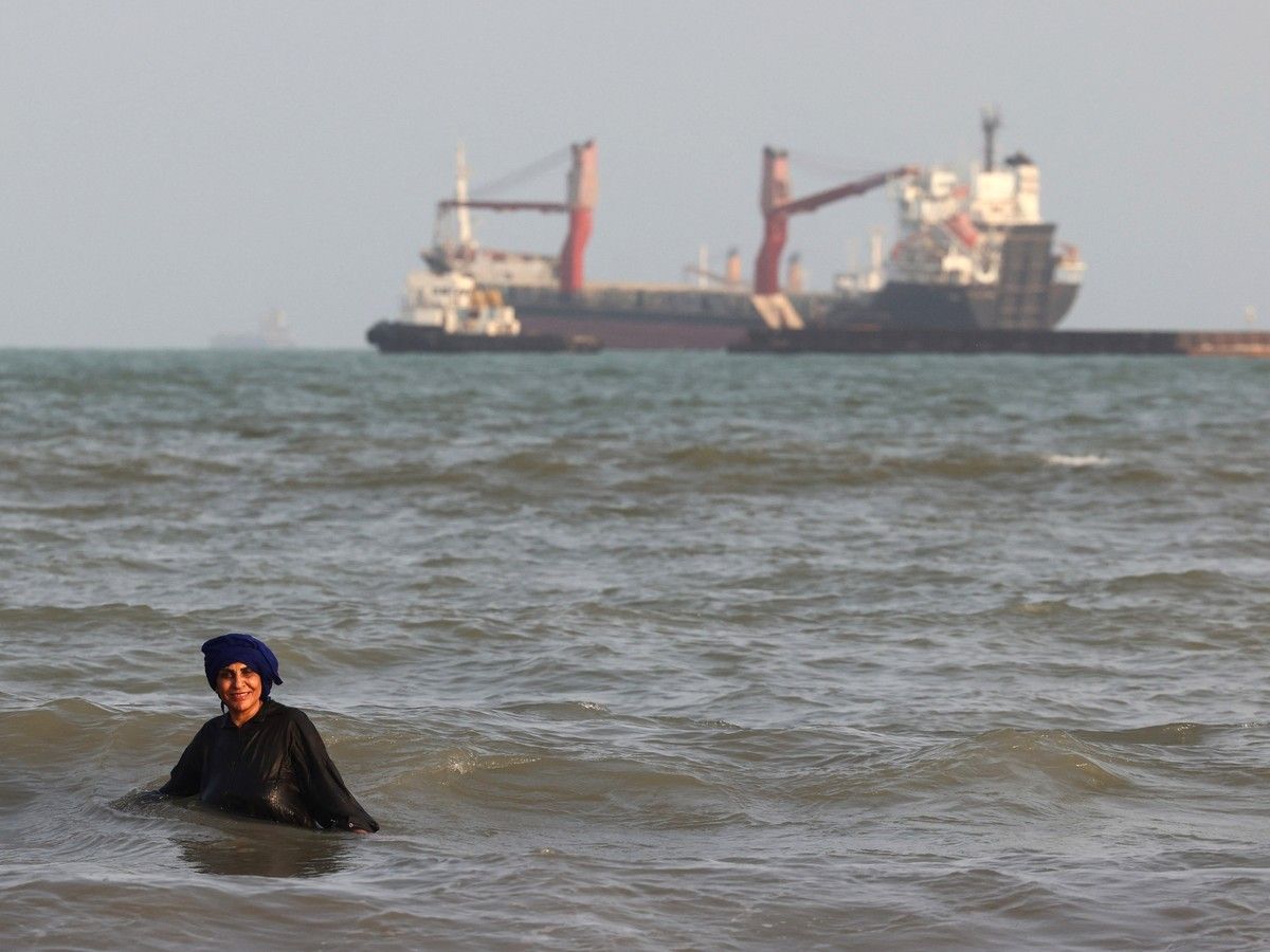  An Iranian woman enjoys a dip in the sea as vessels are seen in the Strait of Hormuz off the port city of Bandar Abbas, in southern Iran on August 10, 2026.