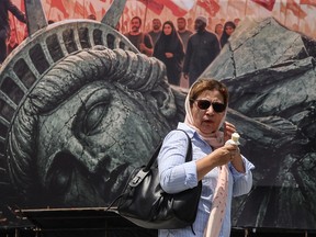 An Iranian woman walks past an anti-U.S. billboard at Enghelab Square in central Tehran