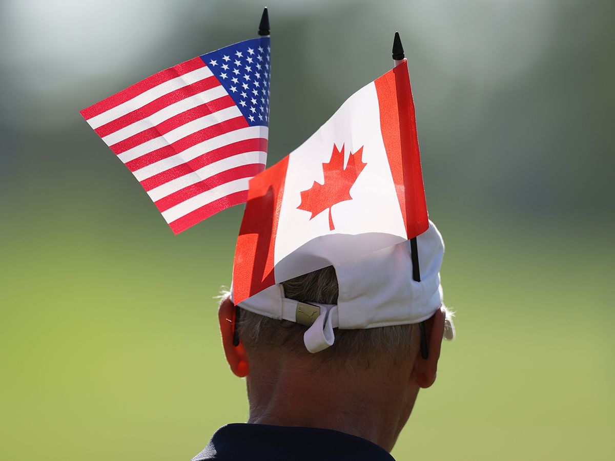 A man wears a hat with American and Canadian flags.