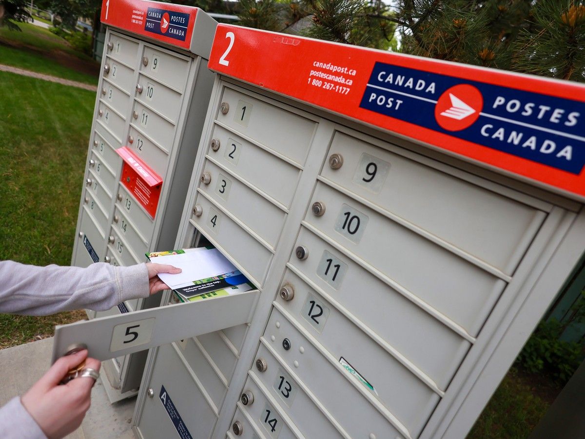Someone taking mail out of their community Canada Post mailbox.
