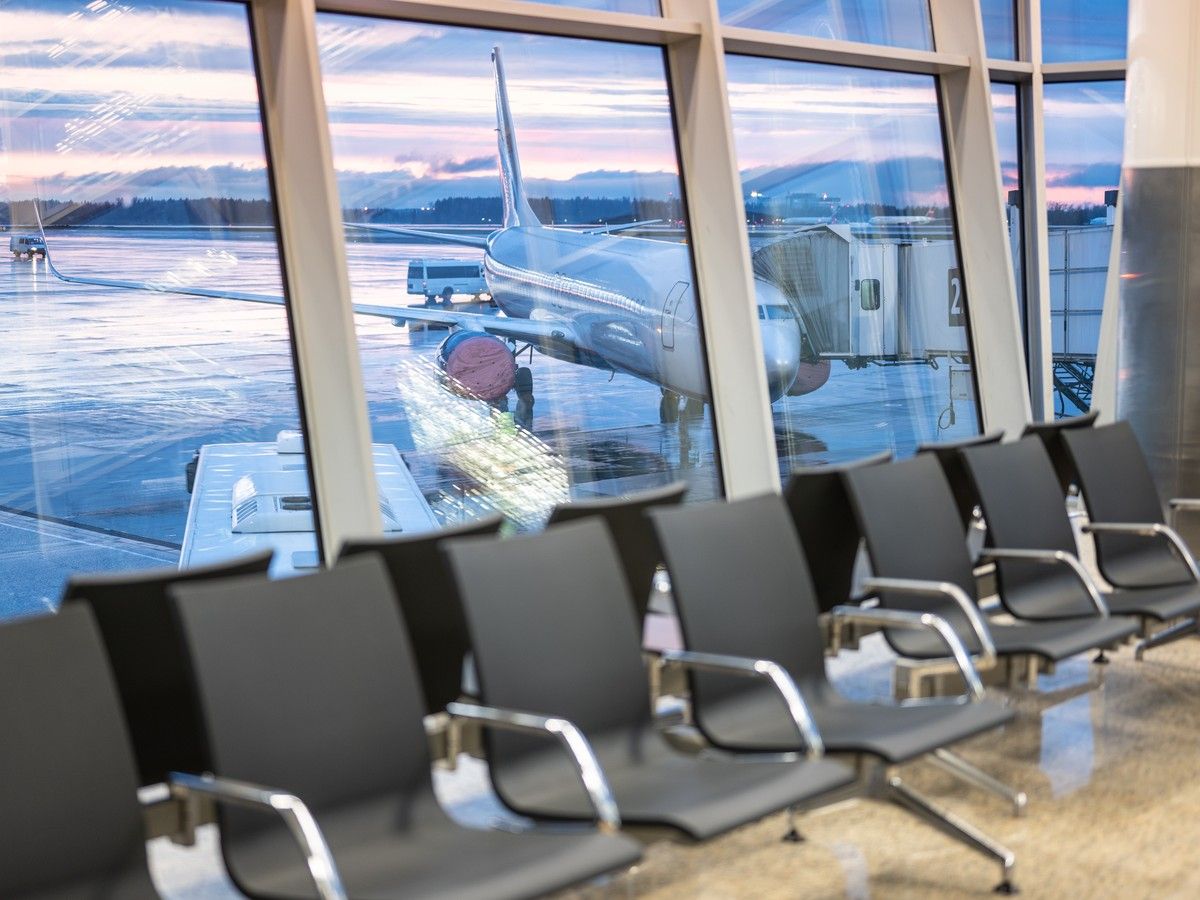 Empty chairs in front of a window with a view of a plane and airport runway.