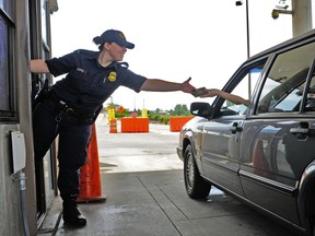 A car driving through the Canada US boarder handing his passport to a CBSA officer.