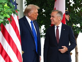 Donald Trump talks to Mark Carney outside the White House with both American and Canadian flags behind them.